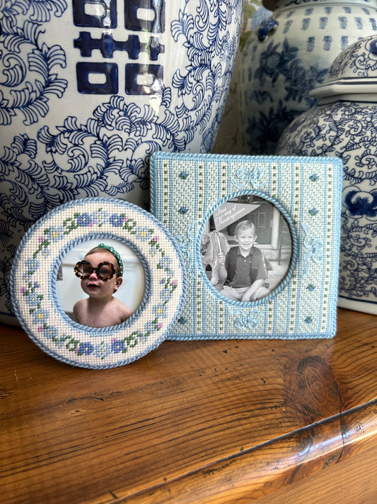 Decorative picture frames with embroidered designs on a wooden surface